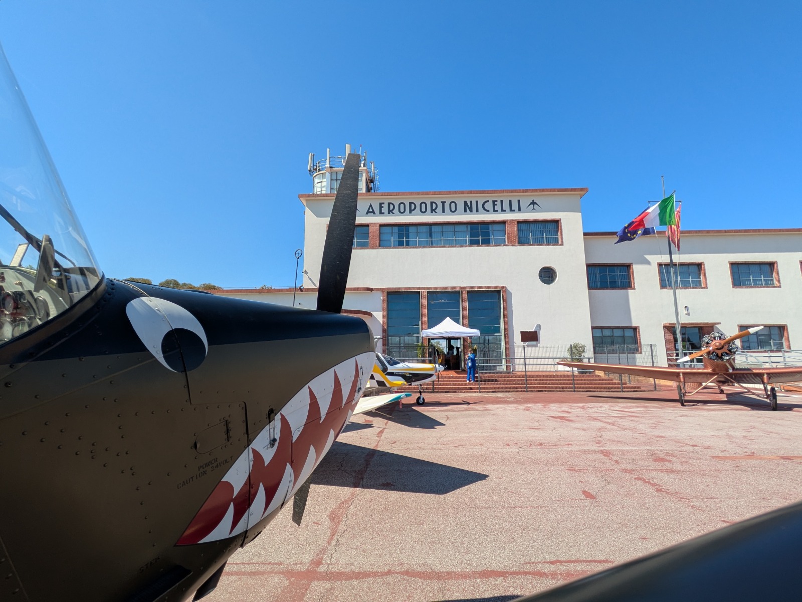 Aeroporto Nicelli con due aerei in primo piano e il cielo azzurro sullo sfondo.
